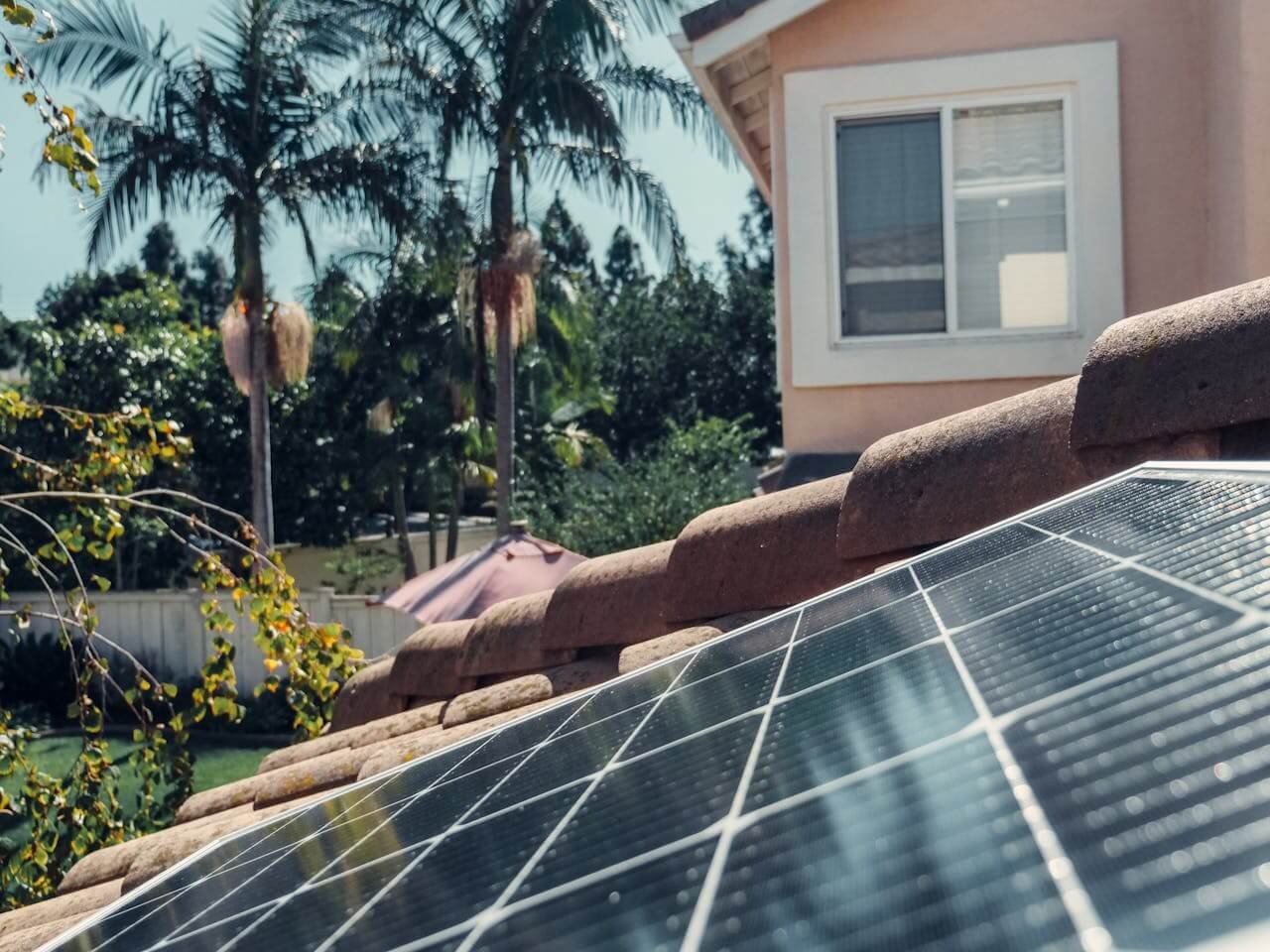 uma casa com jardim e painel solar no telhado